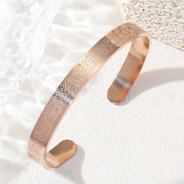 Rose gold bracelet with engraved design on a textured white background
