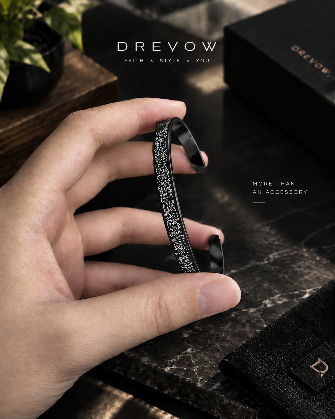 A hand holding a black metal cuff bracelet with a textured, glittery silver pattern. Ayatul Kursi Bracelet - Black Color