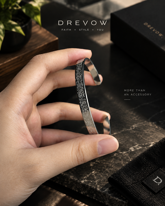 A hand holding a slim metallic cuff bracelet with a textured, glittery silver pattern.Ayatul Kursi Bracelet - Silver