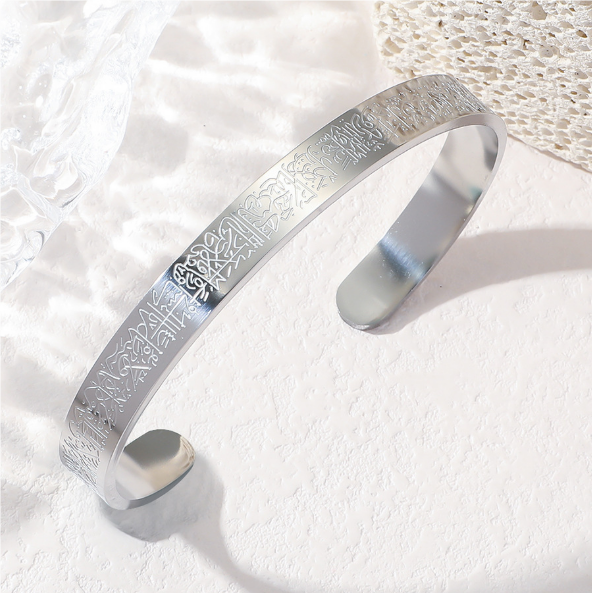 Silver bracelet with engraved design on a textured white surface